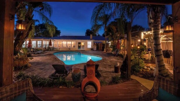 A pool area with lounge chairs, a fire hydrant, and a building with lights in the background.