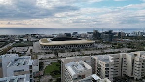 A stadium with a unique circular design, surrounded by modern buildings and a clear view of the sea. - The apartment in the hitech park Haifa (Haifa)