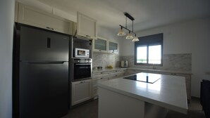 A modern kitchen with a large island, built-in appliances, and a window providing natural light. - The apartment in the hitech park Haifa (Haifa)