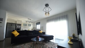 A modern living room with a black sofa, a coffee table, and a kitchen area in the background. - The apartment in the hitech park Haifa (Haifa)