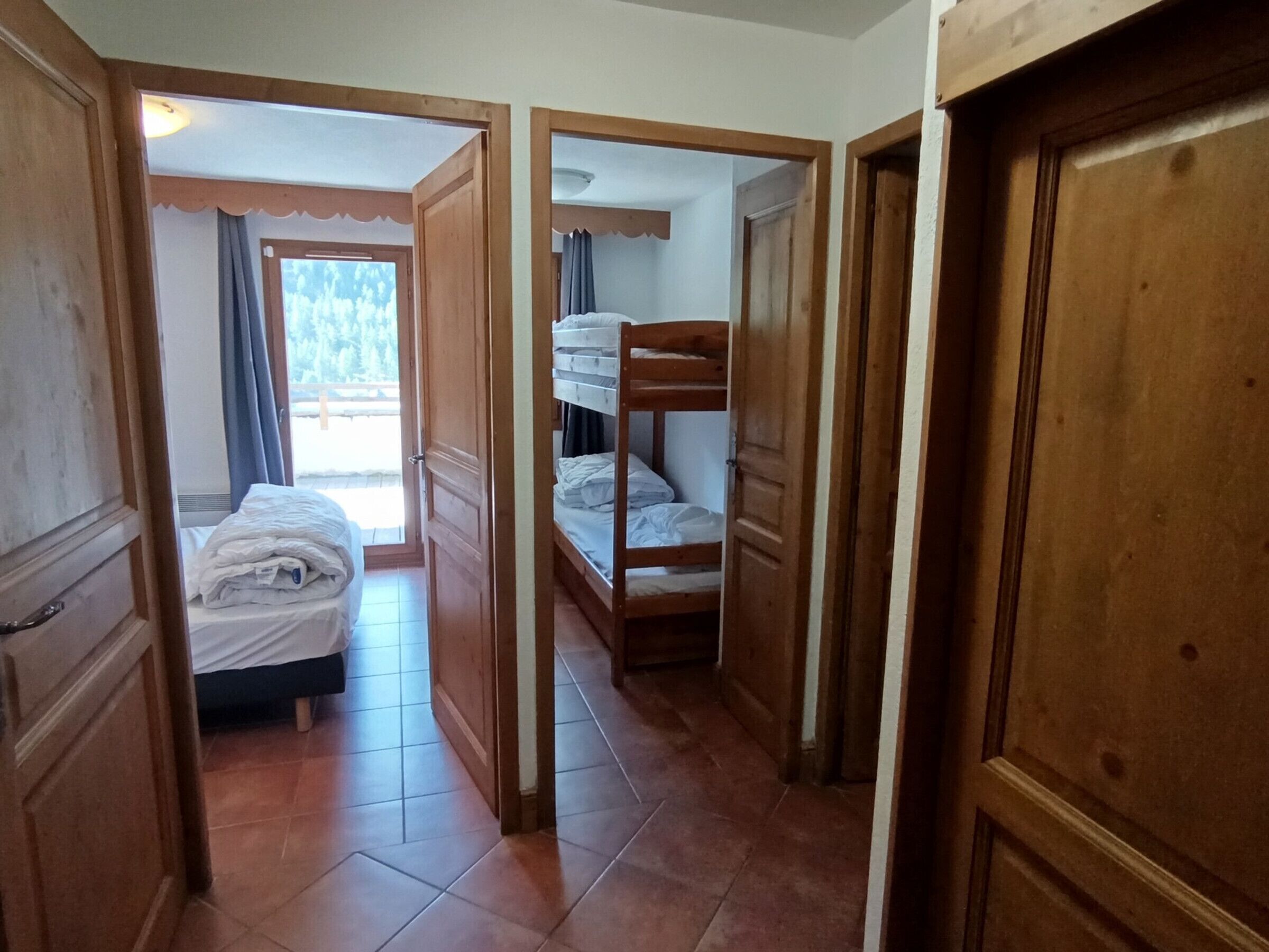 Ein Zimmer mit einem Bett, einem Etagenbett und einer Tür zu einem anderen Raum.