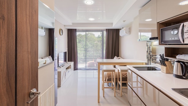 A modern kitchen with a dining area, wooden cabinets, a microwave, and a coffee maker. - Rawai Beach Condo Room 407 (Rawai)