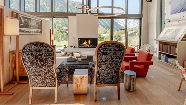 A spacious living room with a fireplace, large windows, and a view of mountains.
