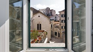 A window view of a narrow street with historic buildings, including a church with a cross on the facade. - Luxury Authentic Studio Split Old-Town (Split)