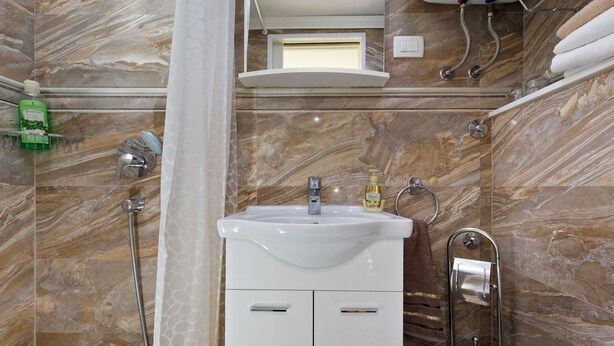 A bathroom with a marble wall, a white sink, a shower, and a towel rack. - Luxury Authentic Studio Split Old-Town (Split)