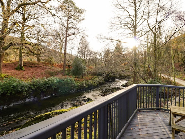 Un pont en bois enjambant une rivière, offrant une vue sur la forêt et les collines environnantes.