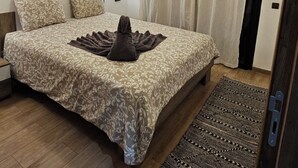 A bedroom with a large bed, a bedside table, a wall-mounted lamp, and a patterned rug.