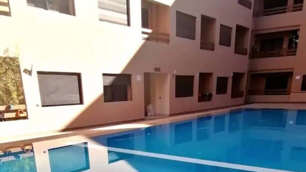 A swimming pool with a clear reflection of a building with multiple windows and balconies.