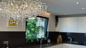 Una cocina moderna con encimera negra, electrodomésticos de acero inoxidable y un candelabro decorativo.