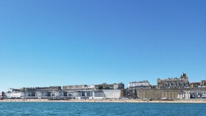 Un paisaje costero urbano con playa, edificios y una gran estructura similar a un castillo.