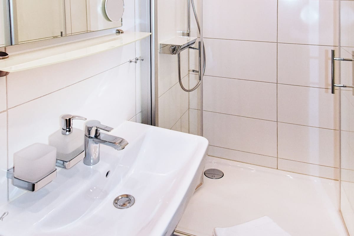 Ein modernes Badezimmer mit Waschbecken, Spiegel und Dusche.
