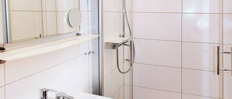 A modern bathroom with a white sink, mirror, and shower.