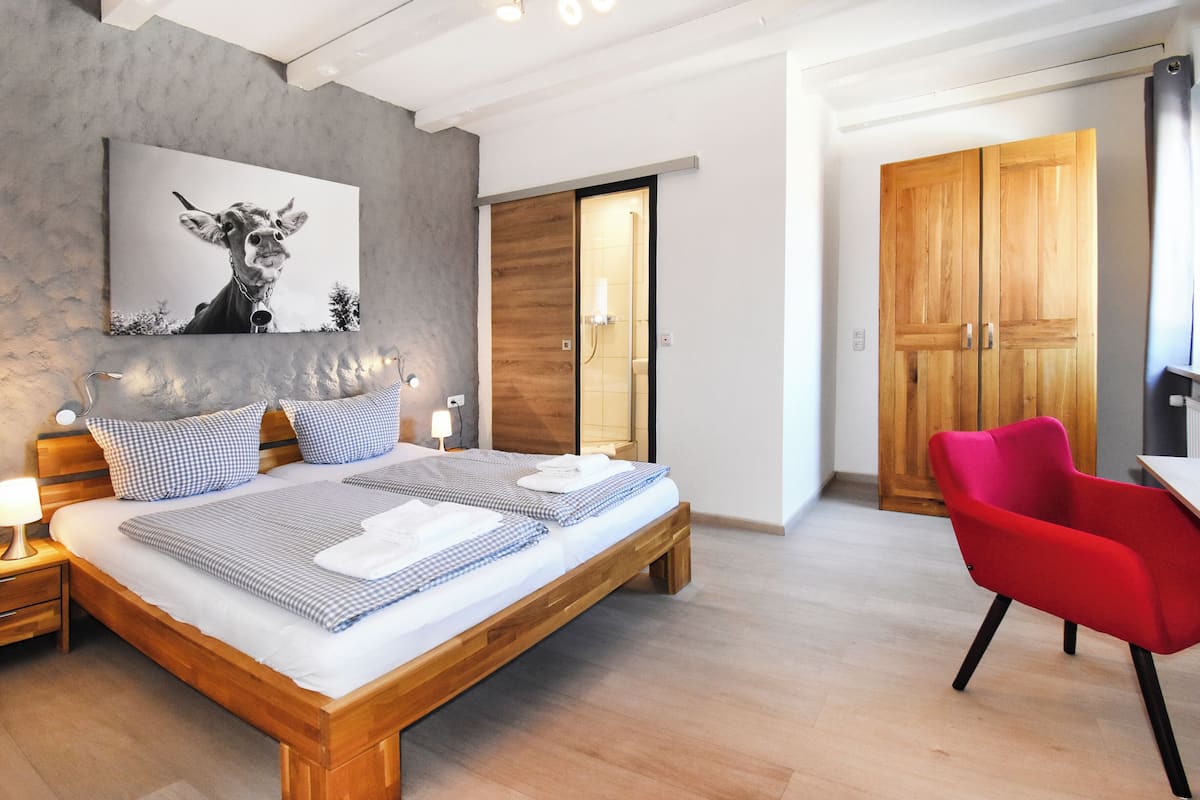 Ein modernes Schlafzimmer mit einem hölzernen Bett, einem roten Sessel und einem Holzschrank.