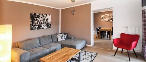 A modern living room with a grey sofa, a wooden coffee table, and a red chair.