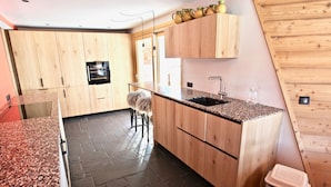 Une cuisine moderne avec des meubles en bois, des plans de travail en granit et un sol carrelé de couleur noire.