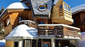 Un chalet en bois doté d’une fenêtre circulaire et d’une enseigne sur laquelle on peut lire « ARMONIA ».
