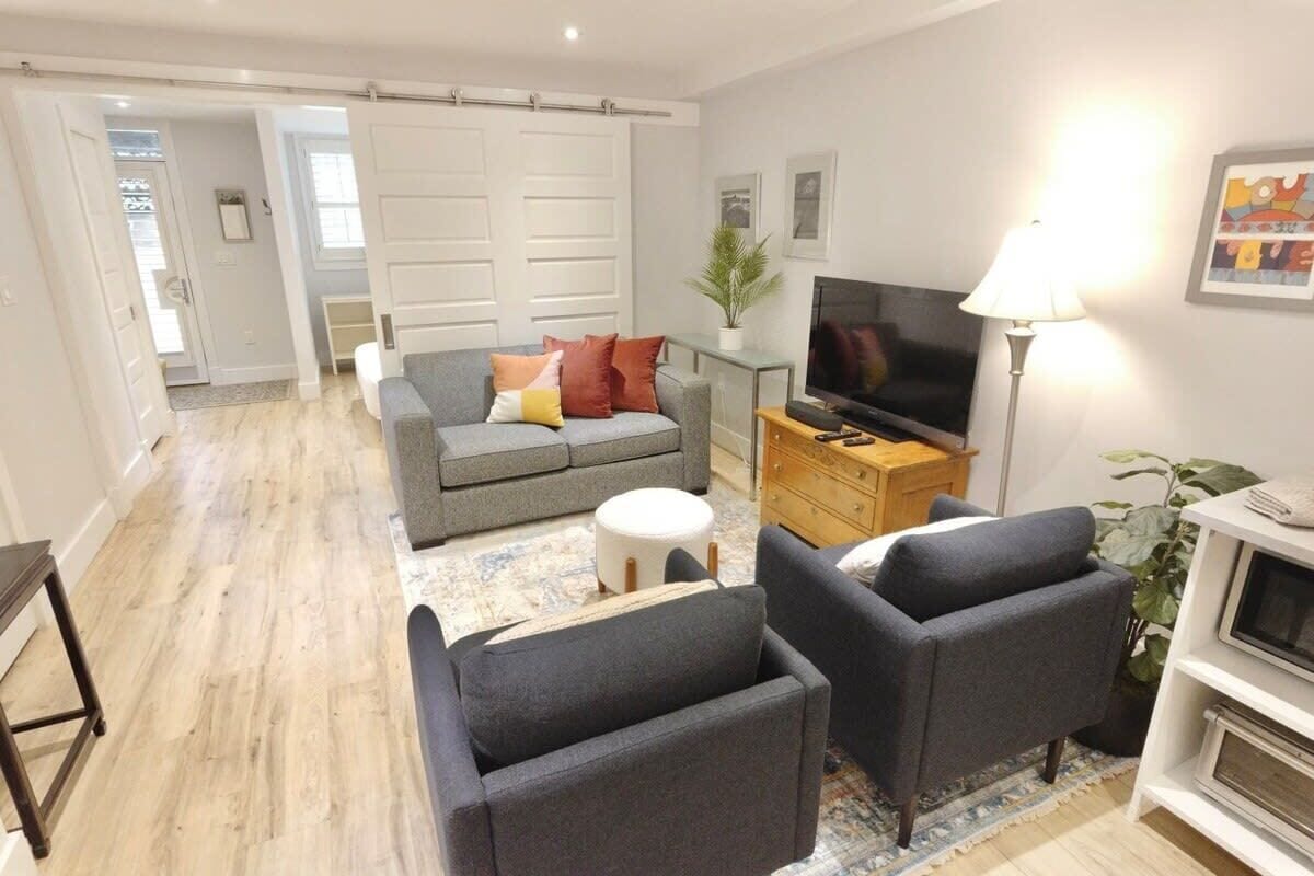 Een woonkamer met een bank, twee fauteuils, een televisie, een lamp en een tv-meubel.