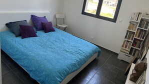 A bedroom with a bed, pillows, a chair, a window, and a bookshelf. - Villa Avec Piscine Santa Maria Poggio (Santa-Maria-Poggio)