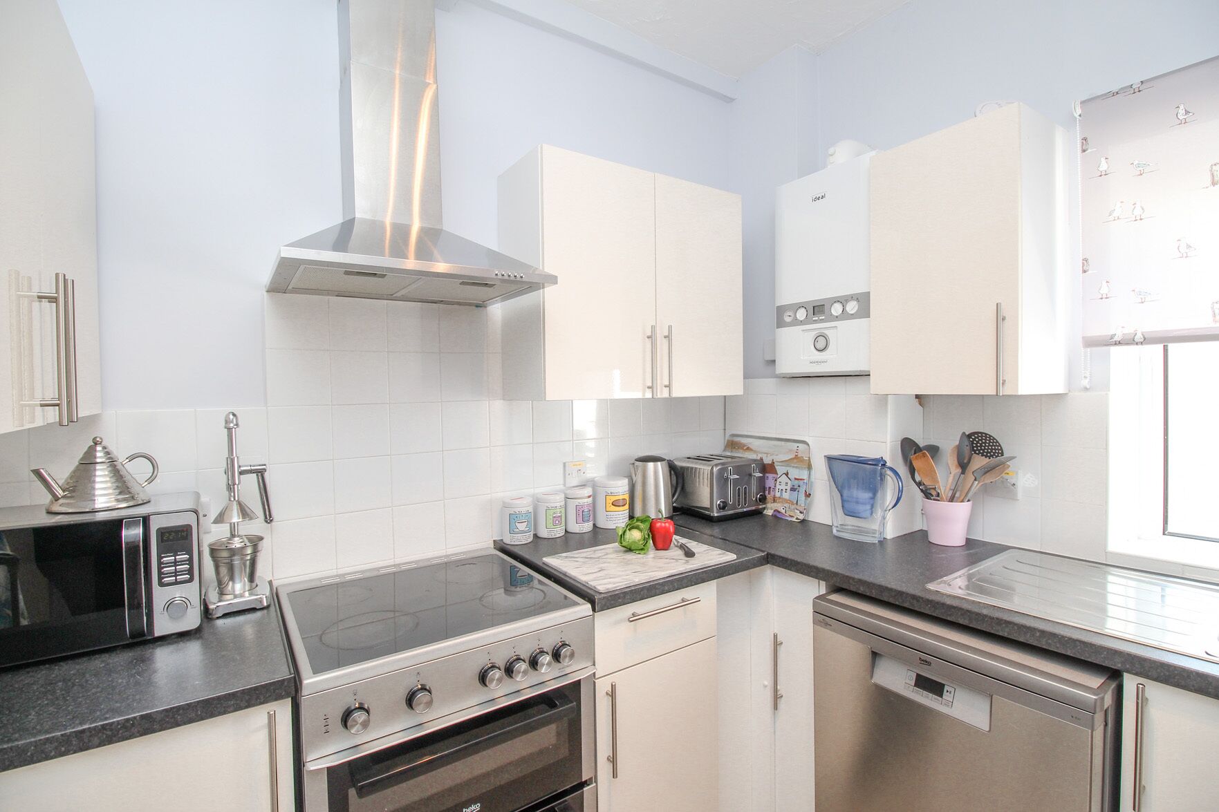 A modern kitchen with white cabinets, stainless steel appliances, and a window providing natural light.
