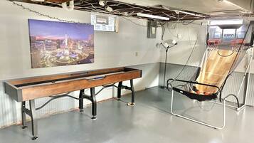 A room with a long wooden bench, a hanging chair, a basketball hoop, and a cityscape poster on the wall.