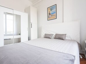 A bedroom with a large bed, a wardrobe, and a painting on the wall.