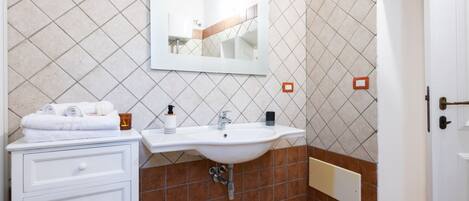 A bathroom with a white sink, a mirror, and a white cabinet with drawers.
