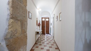 A hallway with a stone wall on one side, a checkered floor, and framed pictures on the walls. - Don Pedro 53 (Tresnuraghes)