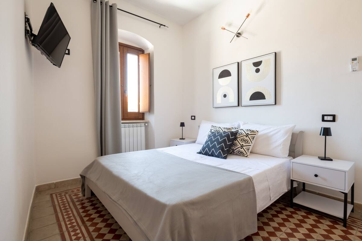 Een netjes ingerichte slaapkamer met een bed, nachtkastjes en kunst aan de muur.