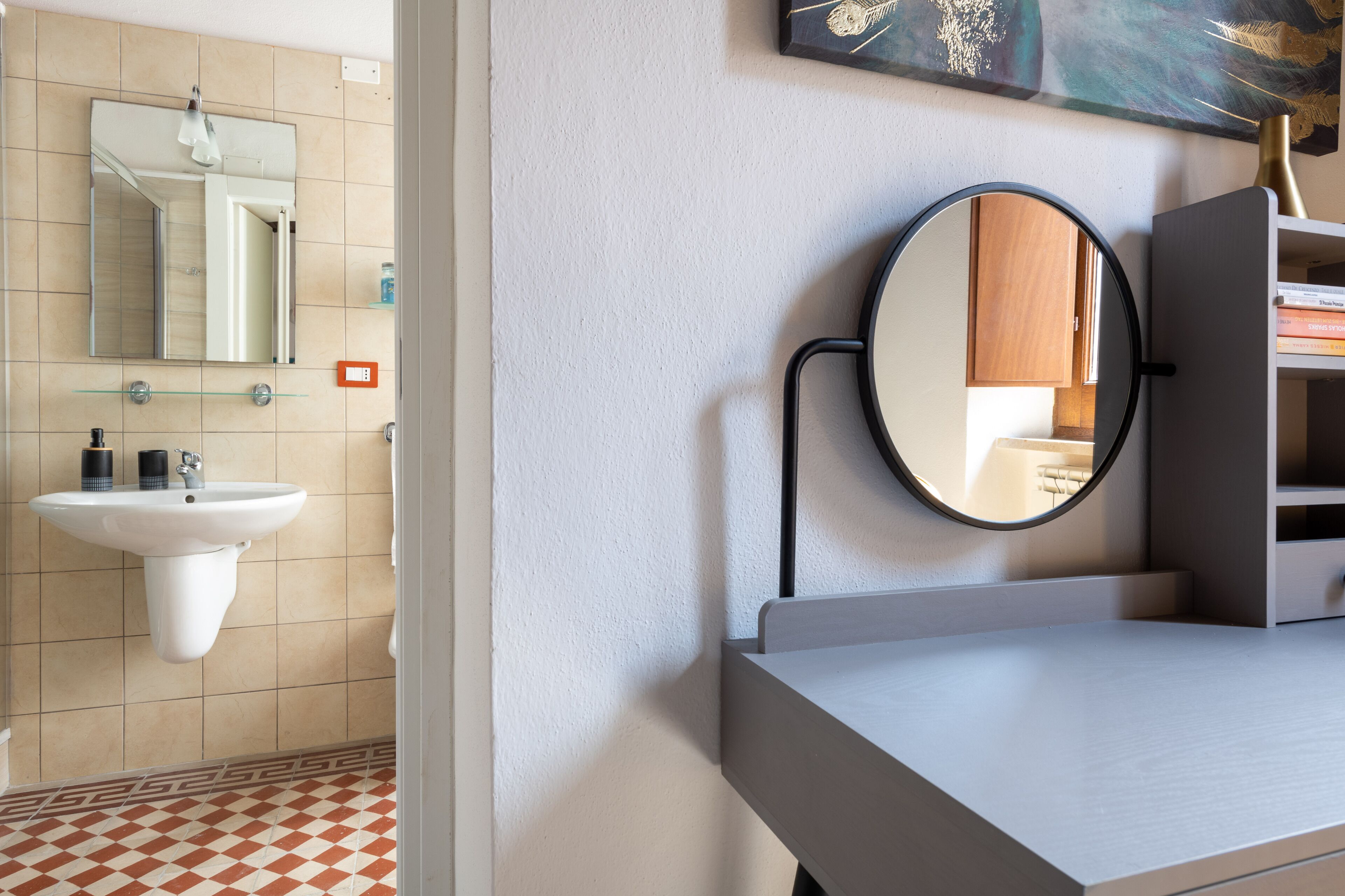 Ein Badezimmer mit einem weißen Waschbecken, einem Spiegel und einem runden Spiegel an der Wand.