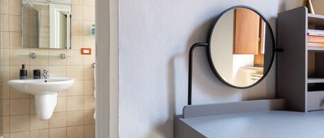 A bathroom with a white sink, a mirror, and a round mirror on the wall.