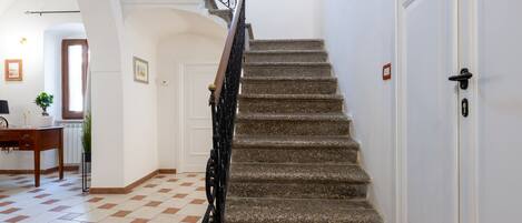 A staircase with a handrail leading to a door.