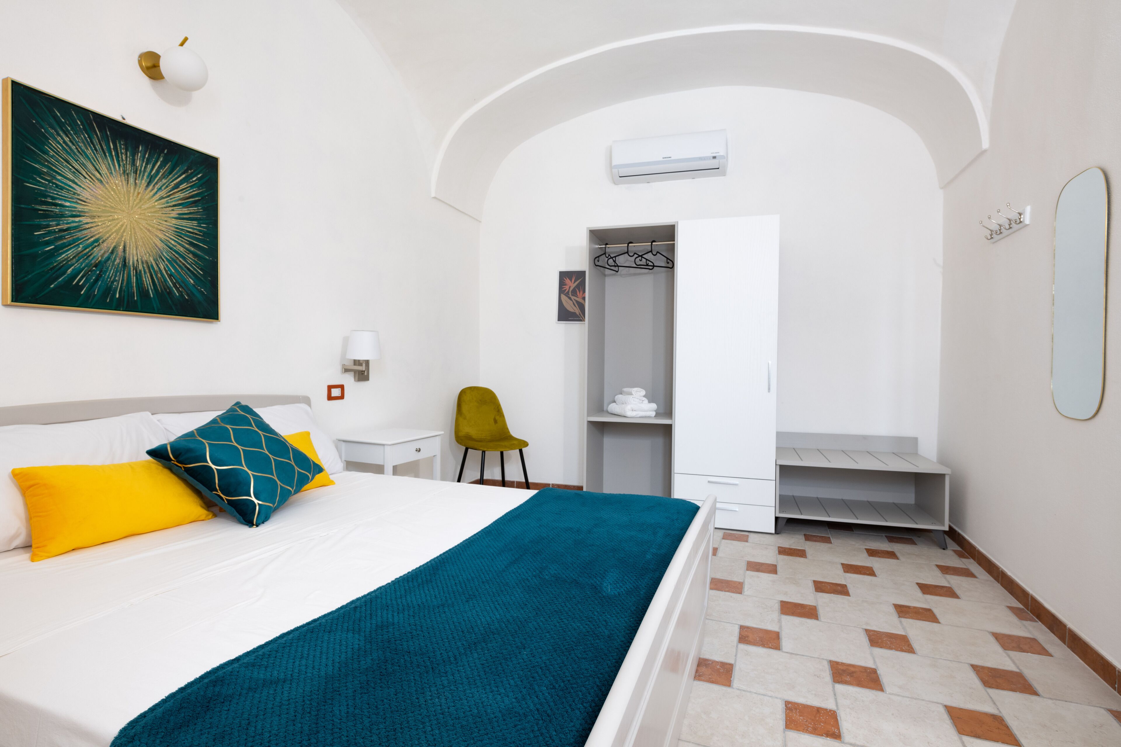 Una habitación de hotel con cama, armario, espejo y aire acondicionado.