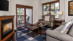 Ein Wohnzimmer mit Kamin, einer Couch, einem Couchtisch und einem Balkon mit Gartenmöbeln.