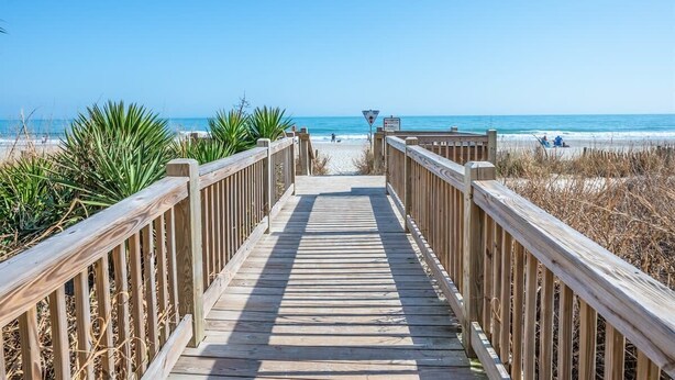 A wooden boardwalk leading to a beach with clear skies. - Oceanfront Efficiency T508 (Myrtle Beach)