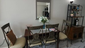 A dining area with a marble floor, a table with chairs, a mirror, and a shelf with kitchen items. - Oceanfront Efficiency T508 (Myrtle Beach)
