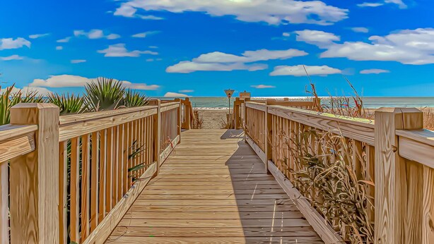 A wooden boardwalk leading to a beach with a clear sky and some clouds. - Oceanview Efficiency DW407 (Myrtle Beach)