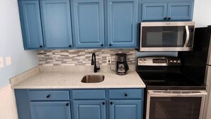 A kitchen with blue cabinets, a microwave, a coffee maker, and an oven. - Oceanview Efficiency DW407 (Myrtle Beach)