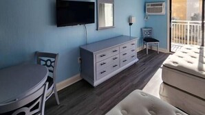 A room with a TV, a dresser, a chair, a table, and a balcony. - Oceanview Efficiency DW407 (Myrtle Beach)