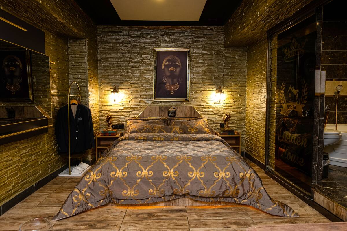 A room with a bed, a framed picture on the wall, and a mirror.