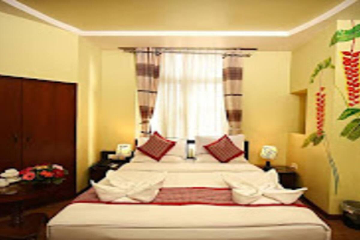 Habitación de hotel con una cama grande, un armario, una mesita de noche y una pared con un mural de plantas.