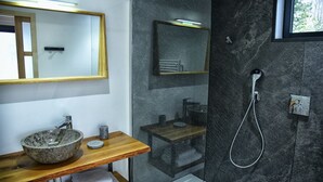 Un bagno moderno con lavabo in pietra, mobile bagno in legno, cabina doccia in vetro e uno specchio grande.