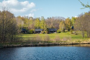 Une propriété au bord du lac comprenant plusieurs maisons, une zone herbeuse et des arbres.