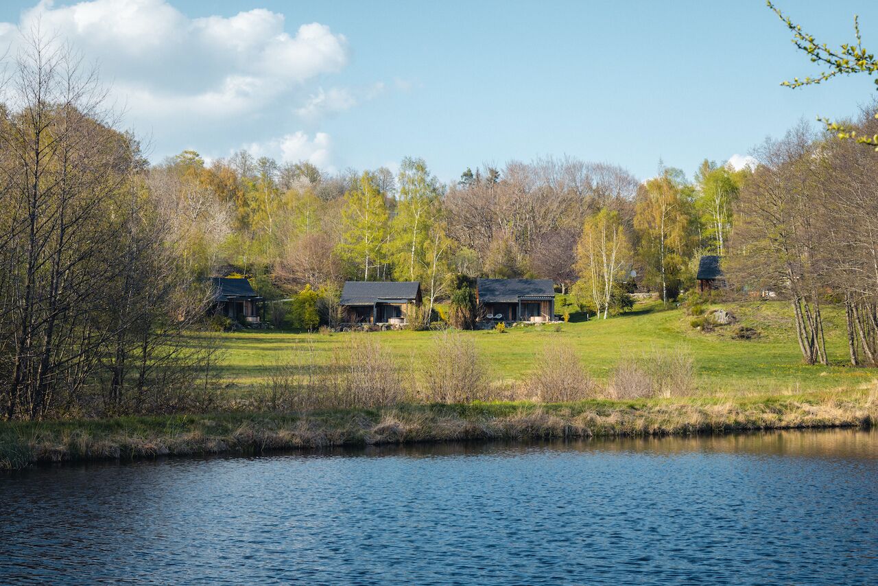 Une propriété au bord du lac comprenant plusieurs maisons, une zone herbeuse et des arbres.