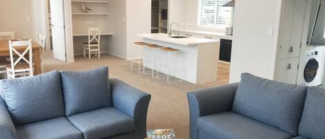 A modern living room with two grey sofas, a wooden coffee table, and a remote control.