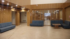 A spacious lobby with wooden paneling, blue sofas, and a central staircase. - The Sky Comfort Beach Hotel, Dwarka (Dwarka)