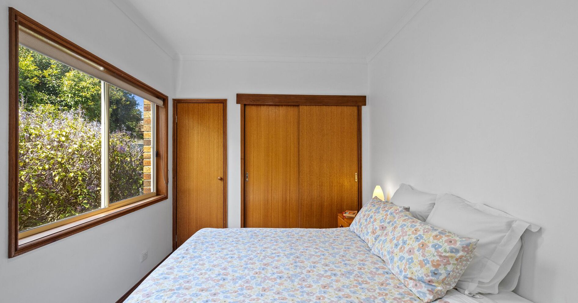 A bedroom with a bed, a window, and a wardrobe.