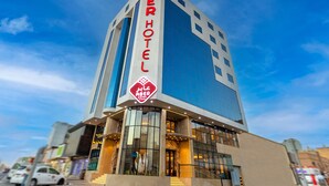 A modern hotel with a prominent sign reading "ABER HOTEL" and a logo with Arabic script.
