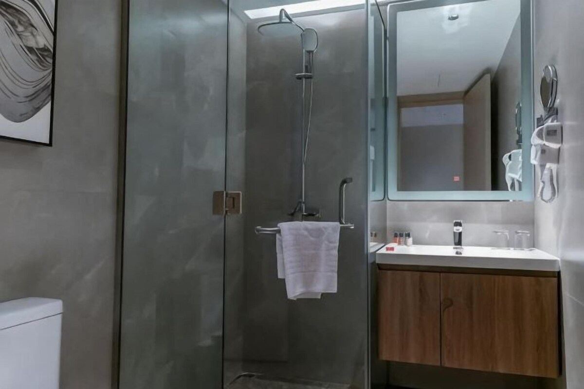 A modern bathroom with a glass-enclosed shower, a wooden vanity, and a large mirror.