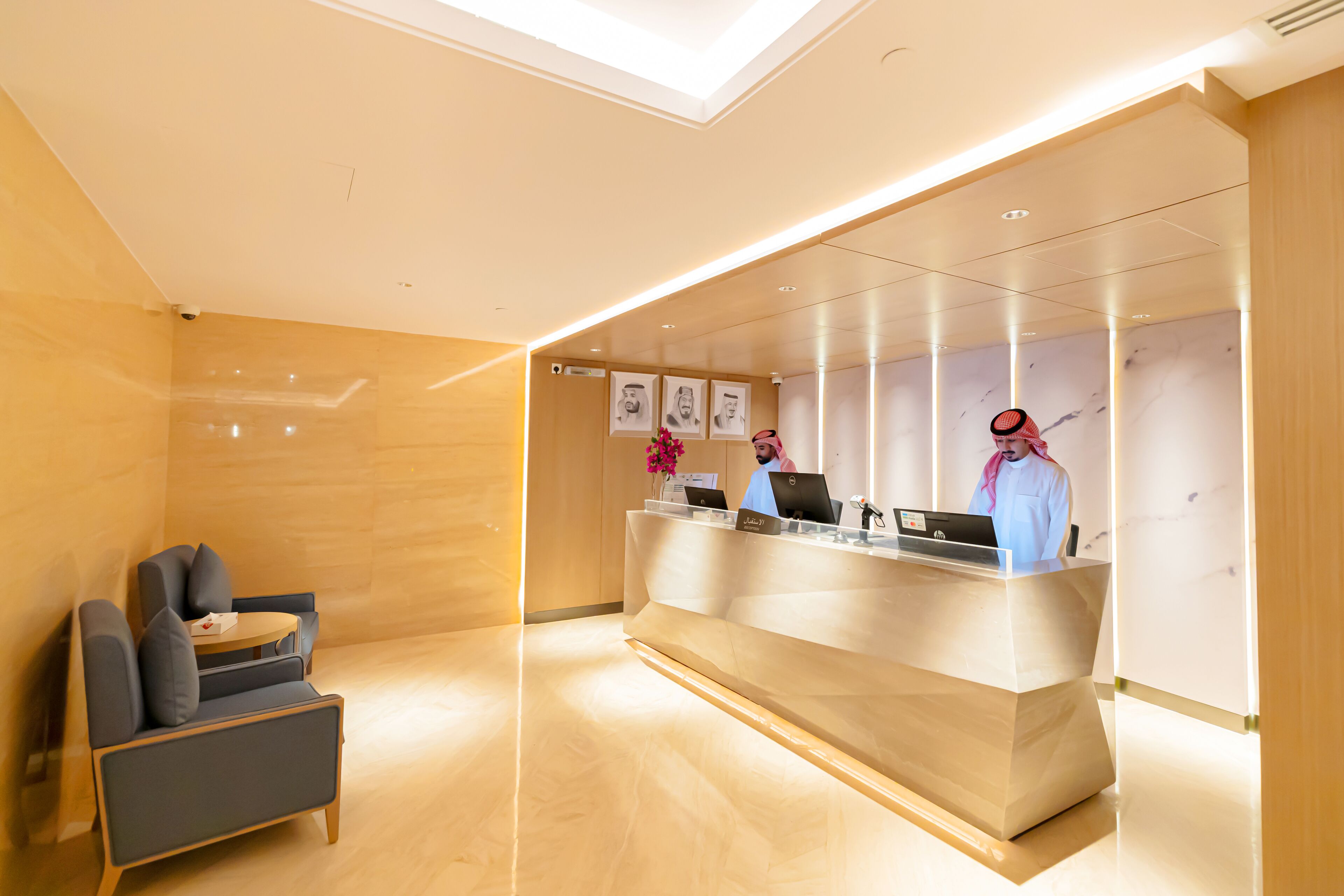 A modern reception area with a reception desk, two chairs, and framed artwork on the wall.
