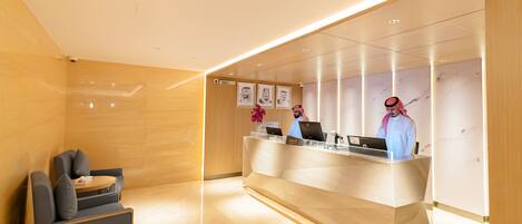 A modern reception area with a reception desk, two chairs, and framed artwork on the wall.